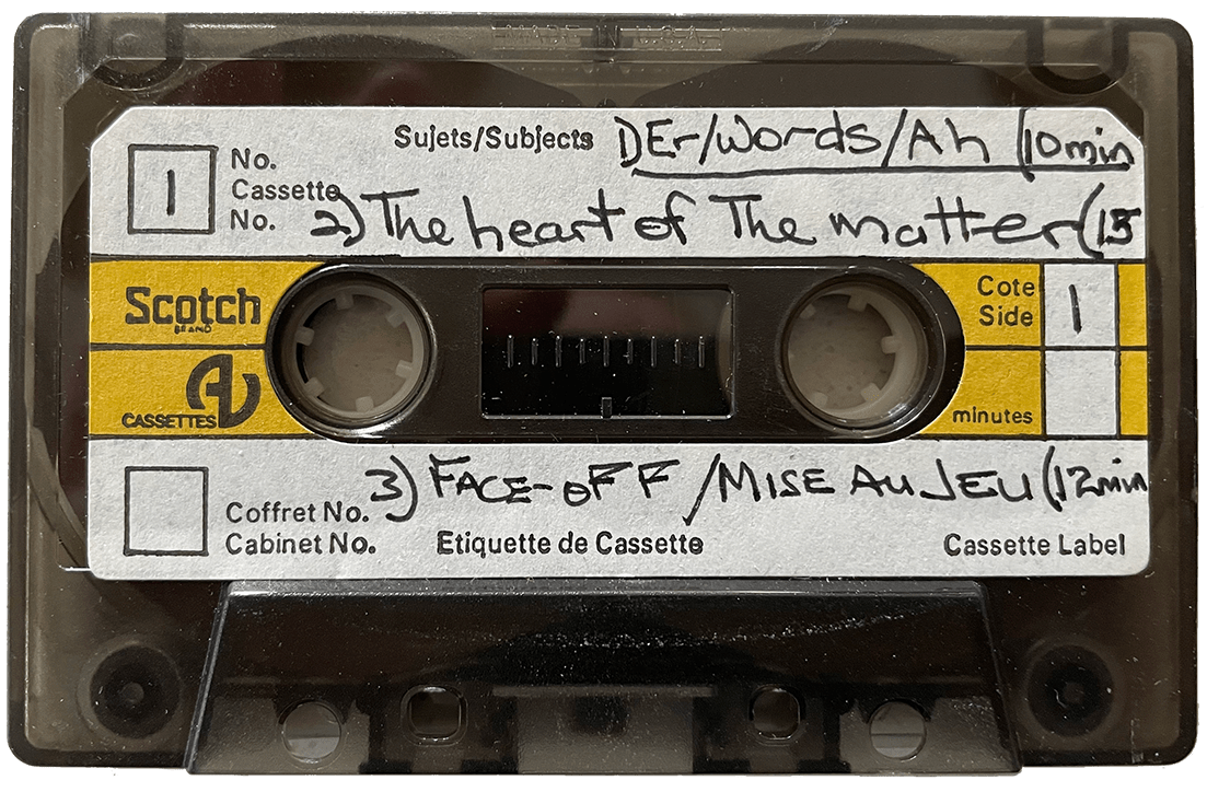 A cassette tape. On the label, in handwriting reads "1. Er/Words/Ah (10 minutes), 2. The heart of the matter, and 3. Face-off / Mise Au Jeu (12 minutes)."